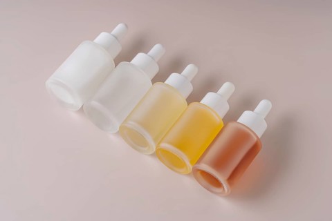 A neatly organized gradient set of five dropper bottles with varying contents from clear to amber