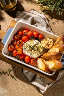 Delight in an elegant dish of baked Camembert paired with cherry tomatoes, roasted garlic, and