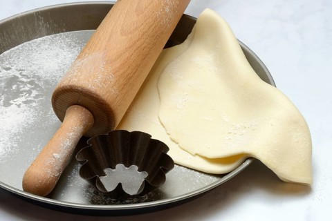 Rolled dough on baking tray with rolling pin