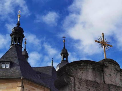Church towers and a cross against a blue sky with clouds, Gößweinstein, Franconian Switzerland
