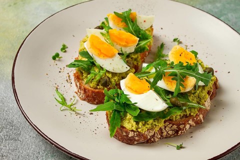 Sandwich with mashed avocado, boiled egg, and arugula, on bread, homemade, breakfast