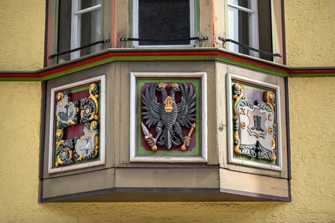 Detailed view of an ornately decorated bay window with heraldic motifs on a traditional town house