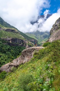 Female hiker standing in front of landscape with mountains and fog, Drakensberg National Park,