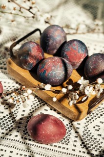 A rustic display of colorful, artistic Easter eggs nestled in a wooden tray adorned with delicate