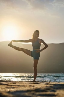 Yoga pose Utthita Hasta Padangusthasana Extended Hand-to-Big-Toe Pose at sunset on the beach