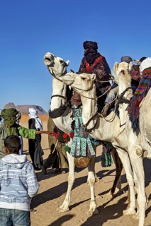 Group of people in traditional costumes riding camels in the desert, Tuareg camel riders at the