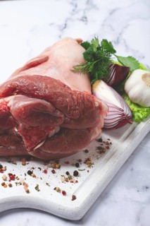 Raw pork knuckle, on a wooden chopping board, with spices, close-up, top view, no people