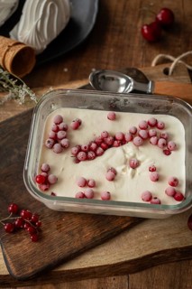 Top view of creamy vanilla ice cream sprinkled with frozen red currants in a rectangular glass