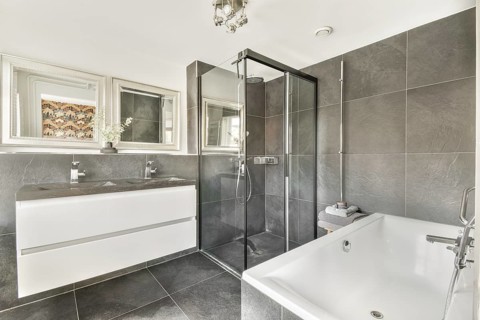 A stylish modern bathroom featuring sleek fixtures, a glass shower, elegant tiles, and a bathtub,