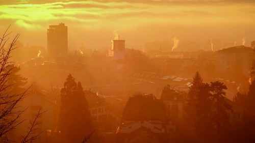 A serene sunrise casts a golden hue over the cityscape of Lausanne, Switzerland, highlighting the