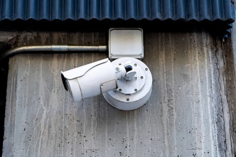 An outdoor surveillance camera, with a robust design, is securely mounted on a corrugated,