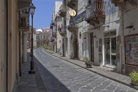 A quiet, paved street in an old town with old houses and balconies, Lipari Town Lipari Islands