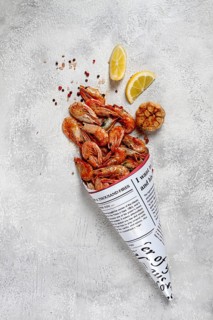 Fried shrimp, in a paper bag, shrimp for beer, in a newspaper, on a gray table, no people
