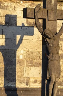 Stone cross with shadow cast at sunrise, cathedral cemetery near Cologne Cathedral, Cologne, North