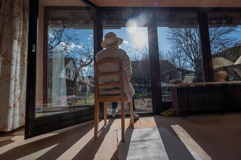 Woman wearing hat sunbathing with patio door open, Bavaria, Germany