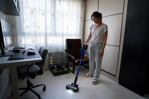 A woman efficiently cleans her living room using a sleek modern vacuum cleaner. The setting is