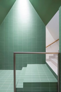 A vibrant and eco-friendly interior showcasing a staircase with green tile walls, emphasizing