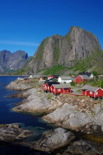 Red rorbu houses on rocks and high, rugged, mountains, holiday, holiday homes Hamnoy, Lofoten,