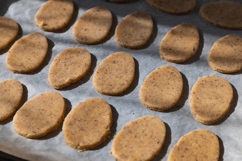 Easter cookies in egg shape prepared for baking on a baking tray with baking paper