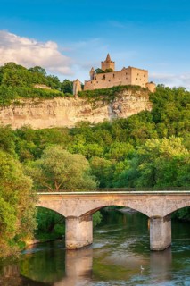 View of the Rudelsburg castle ruins above the Saale river with railway bridge in the evening light,
