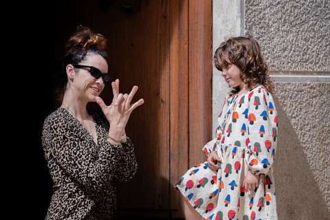 A joyful moment captures a mother and her child playing in a picturesque village street. Laughter