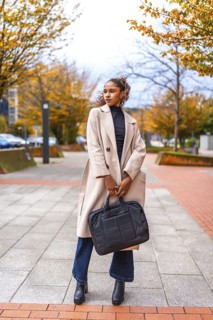 Vertical full length photo of a business style african american model with trench coat and handbag