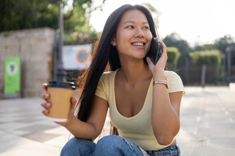 A young Chinese woman enjoys a pleasant summer day in the city, engaging in a cheerful conversation