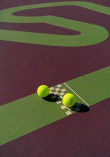 Vibrant close-up of three tennis balls on a uniquely designed court, featuring a contrast of green