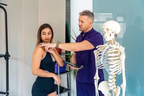 Physiotherapist showing a female patient shoulder points on her body while discussing a treatment