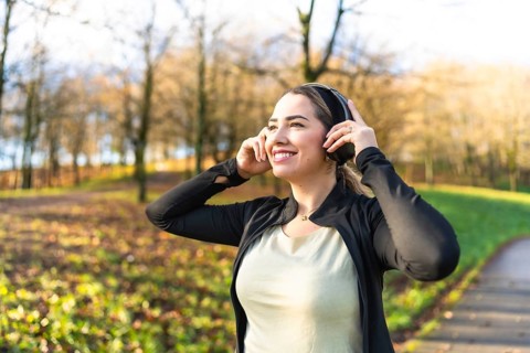 Happy young woman smiling and enjoying listening to music through headphones, finding emotional