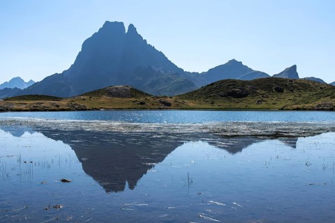 A breathtaking view of Midi d'Ossau in the French Pyrenees, reflected in a serene mountain lake The