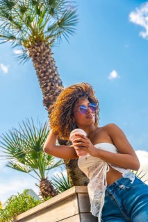 Vertical photo of a sensual woman drinking iced shake outdoors in a sunny day in summer