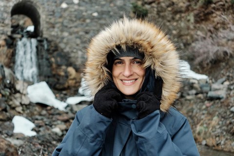 Smiling woman in a fur-lined hooded coat at Astun ski resort, Huesca Pyrenees. Snow and stone