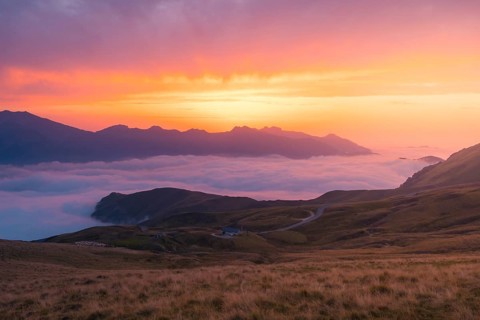 Experience serenity with a mountainous landscape bathed in vibrant sunset hues in the Pyrenees.