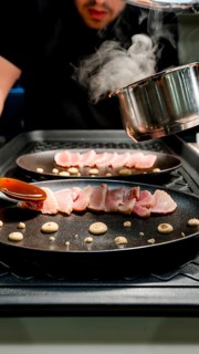 A chef skillfully sears fresh tuna slices, arranging them elegantly on a pan with rich sauces and