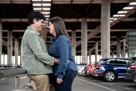 A joyful curvy lesbian couple embraces in an urban parking area. The moment captures a sense of