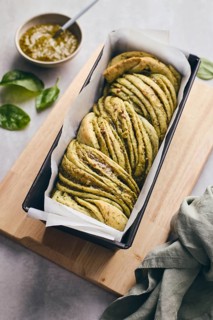 Baked homemade savoury babka plaited bread loaf flavoured with cheese and pesto, in the making tin