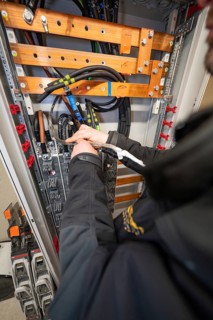 Worker working on cables in an open power box, focus on installation and technology, switch cabinet