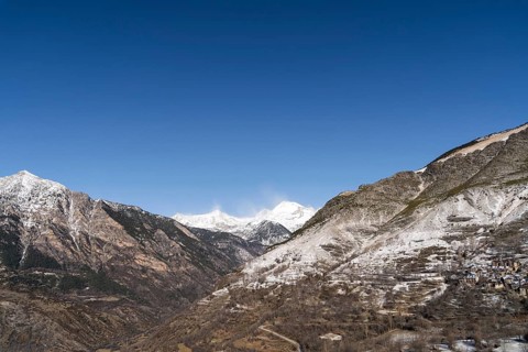 A breathtaking rural landscape featuring majestic snow-capped mountains under a clear blue sky,