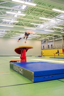 A gymnast in the air jumping off a horse jumping device in a gym, Gymnastics, Calw, Germany