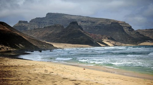 Secluded, secluded coast with sandy beach and rock formations that look out to sea under grey