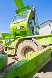 Green telescopic handler on a construction site with blue sky in the background, RABA Solar
