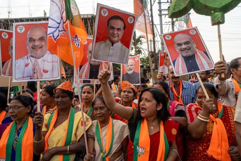 Supporters hold placards featuring Amit Shah and Himanta Bishwa Sarma during a public rally of the