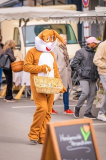Person in rabbit costume with a basket passes by a market stand, Easter campaign, Sindelfingen,