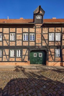 Rossmühle, half-timbered house, dormer with crane, entrance gate, blue cloudless sky, cobblestone