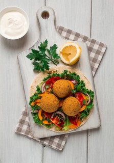 Tortillas, wrapped falafel balls, with fresh vegetables, vegetarian healthy food, on a wooden white