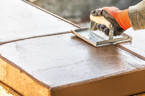 Construction Worker Using Hand Groover On Wet Cement Forming Coping Around New Pool