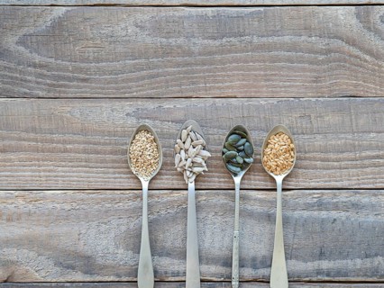 Various healthy seeds filling spoons on a rustic wooden table