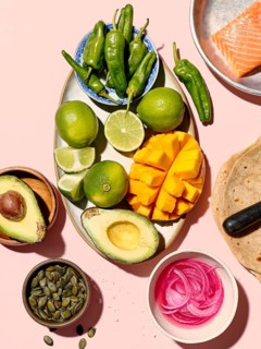 Top view of assorted fresh ingredients for taco preparation displayed on a vivid pink background.