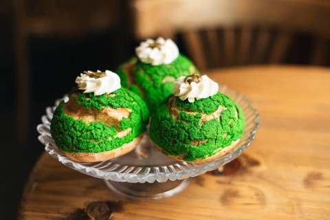 Three cream matcha choux pastries with vibrant green topping and whipped cream, elegantly arranged